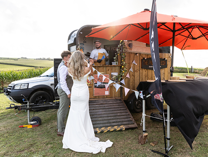 Couple enjoying The Piccolo Box mobile pizza van during their outdoor wedding reception