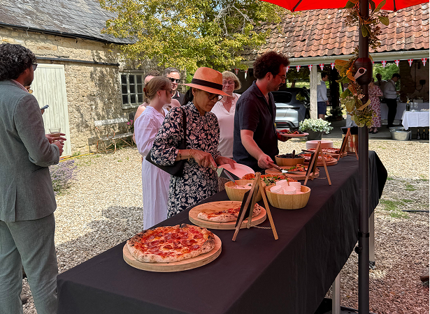 Wedding guests enjoying freshly served stone baked pizza at a countryside wedding reception