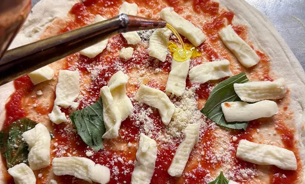 Premium mozzarella and Italian toppings added to a stone baked pizza