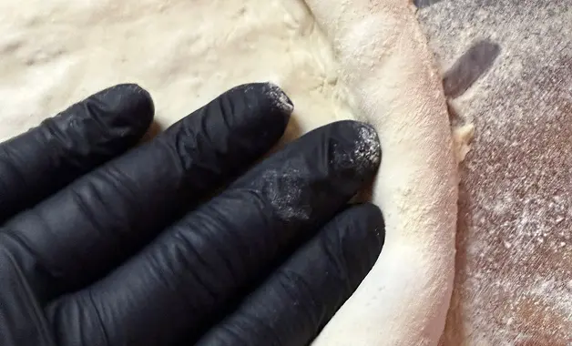 Hands shaping slow-fermented pizza dough for authentic stone baked pizza catering