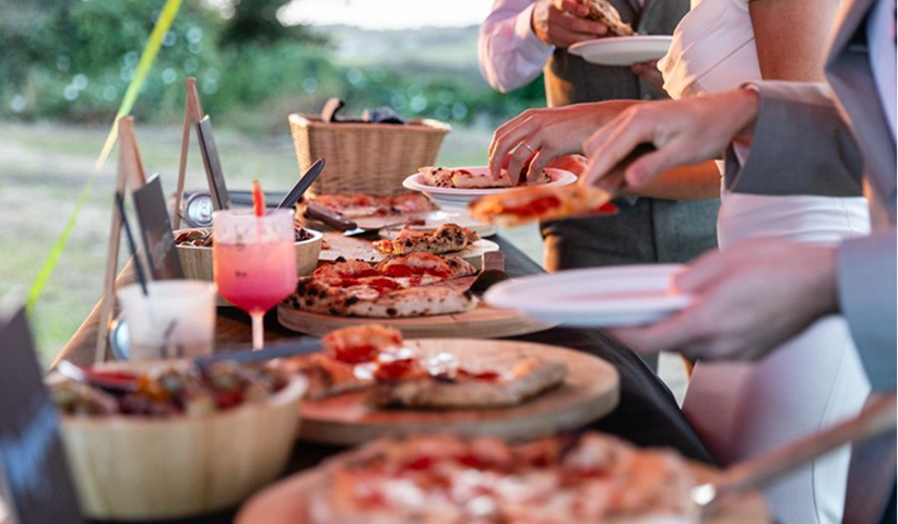 Guests serving themselves stone baked pizza at a Piccolo Box wedding catering reception