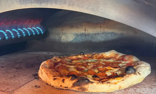 Stone baked pizza cooking at 400 degrees in a professional pizza oven