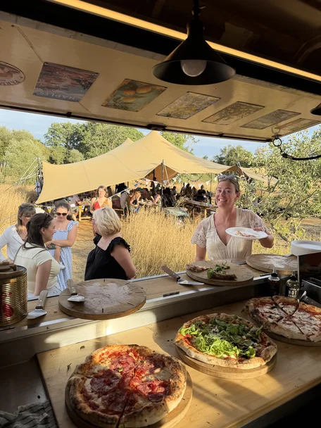 Guests collecting stone-baked pizza from The Piccolo Box van at a summer event