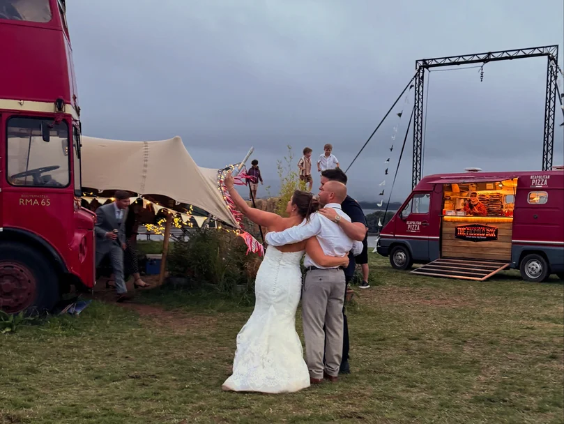 Newlyweds dancing beside The Piccolo Box pizza van at their wedding